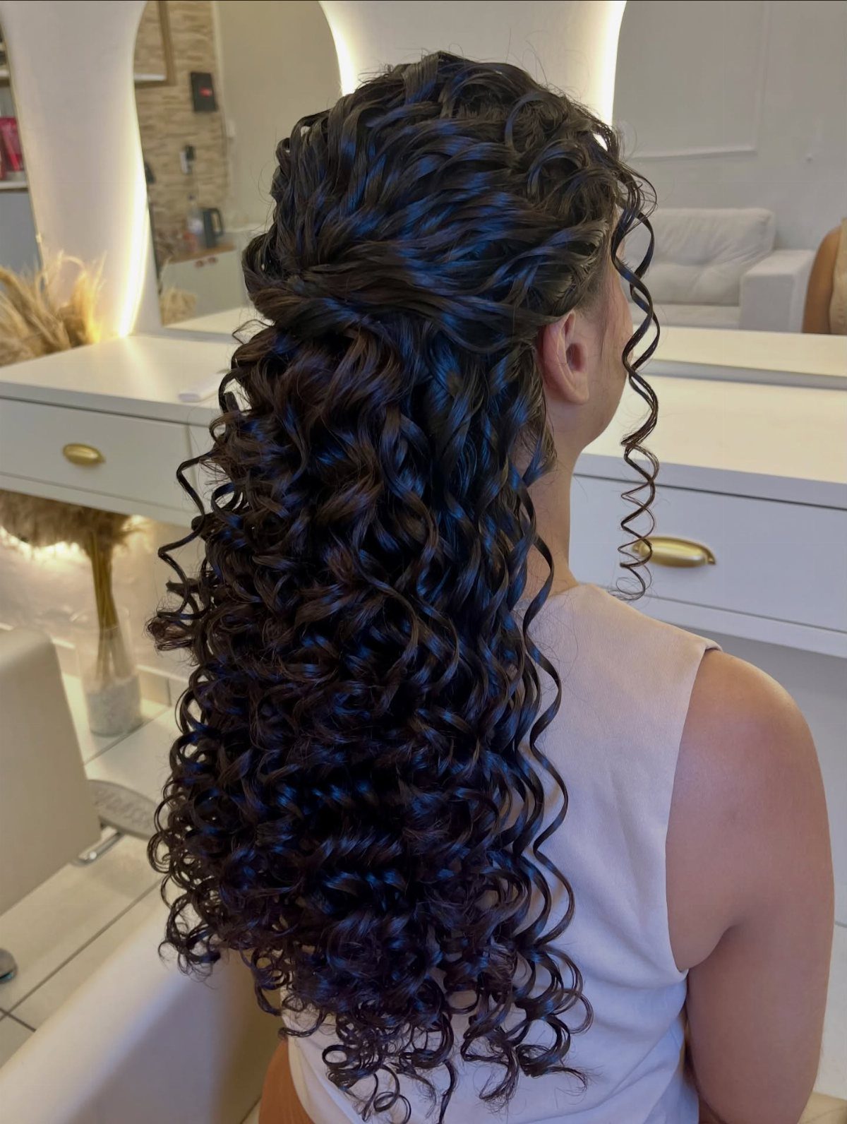 Woman with long dark curly hair in a half-up half-down wedding style.
