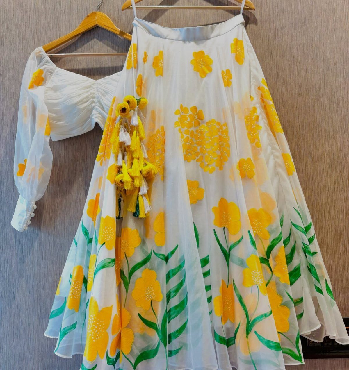 White two-piece outfit with yellow floral prints hanging on wooden hangers.