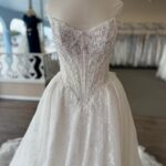 White lace wedding dress with a sequined corset bodice on a mannequin